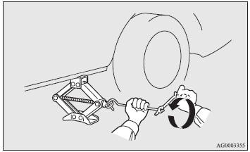 8. Lower the vehicle slowly by rotating the wheel nut wrench anticlockwise until